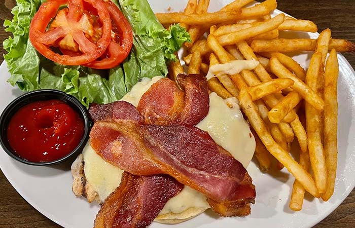 Bacon cheeseburger with lettuce, tomato, fries, and ketchup—pairs well with our fresh cocktails.