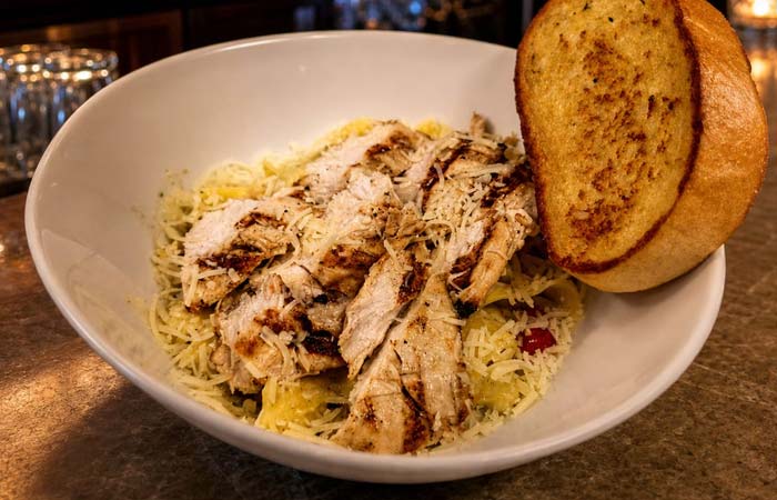 Grilled chicken on pasta with shredded cheese, served in Owatonna with toasted garlic bread.