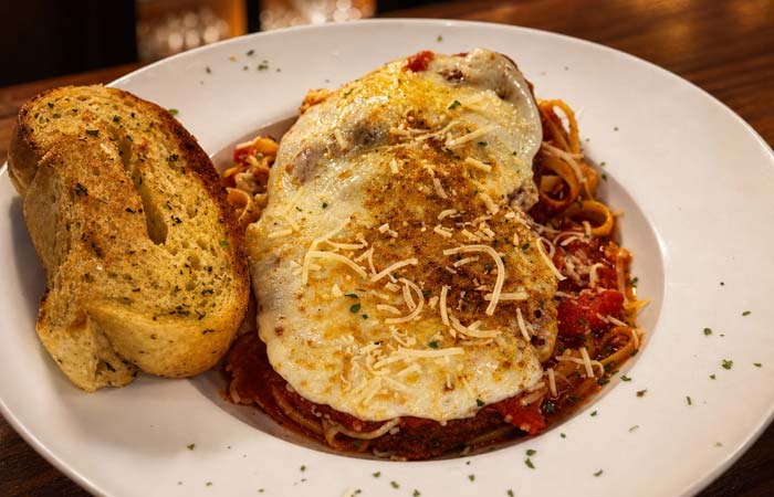 Chicken parmesan on spaghetti with tomato sauce, served with garlic bread—perfect in Owatonna.