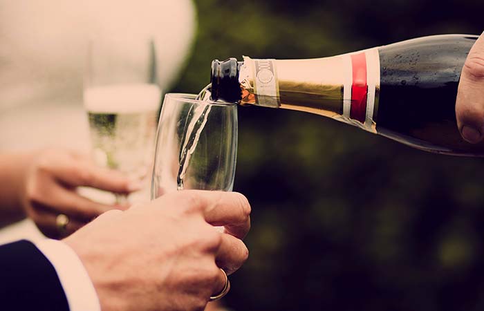Champagne being poured into a flute, with seafood appetizers nearby against a blurred background.