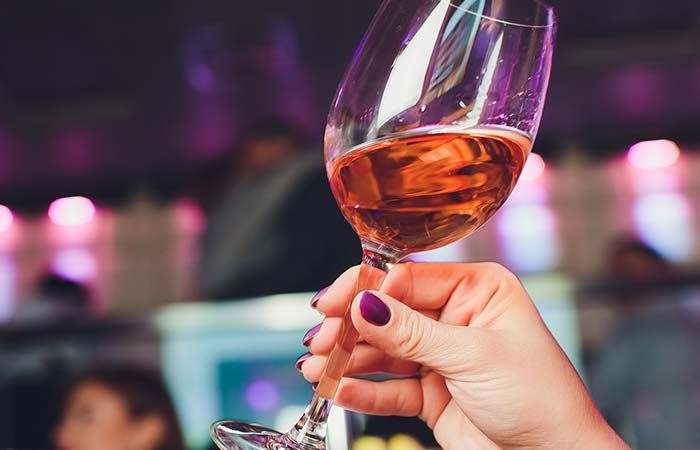 A hand with purple nails holds rosé wine, perfect for a night of seafood and pasta in Owatonna.