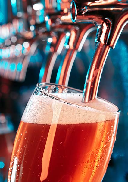 A glass being filled with amber beer at Torey’s Restaurant & Bar, topped with a foamy head.
